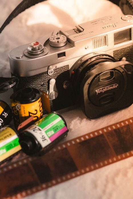 Cámara Leica M2 rodeada de carretes de película y una tira de negativos