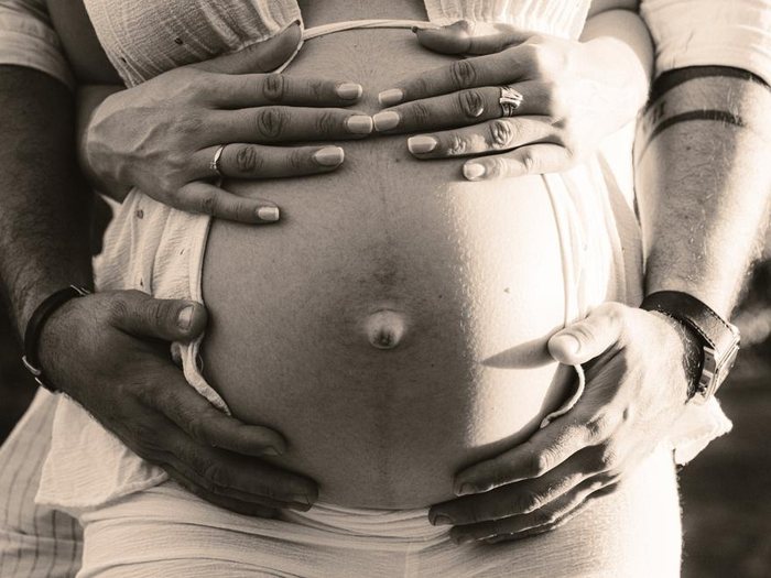 Manos de la pareja alrededor de la barriga de embarazo, en blanco y negro